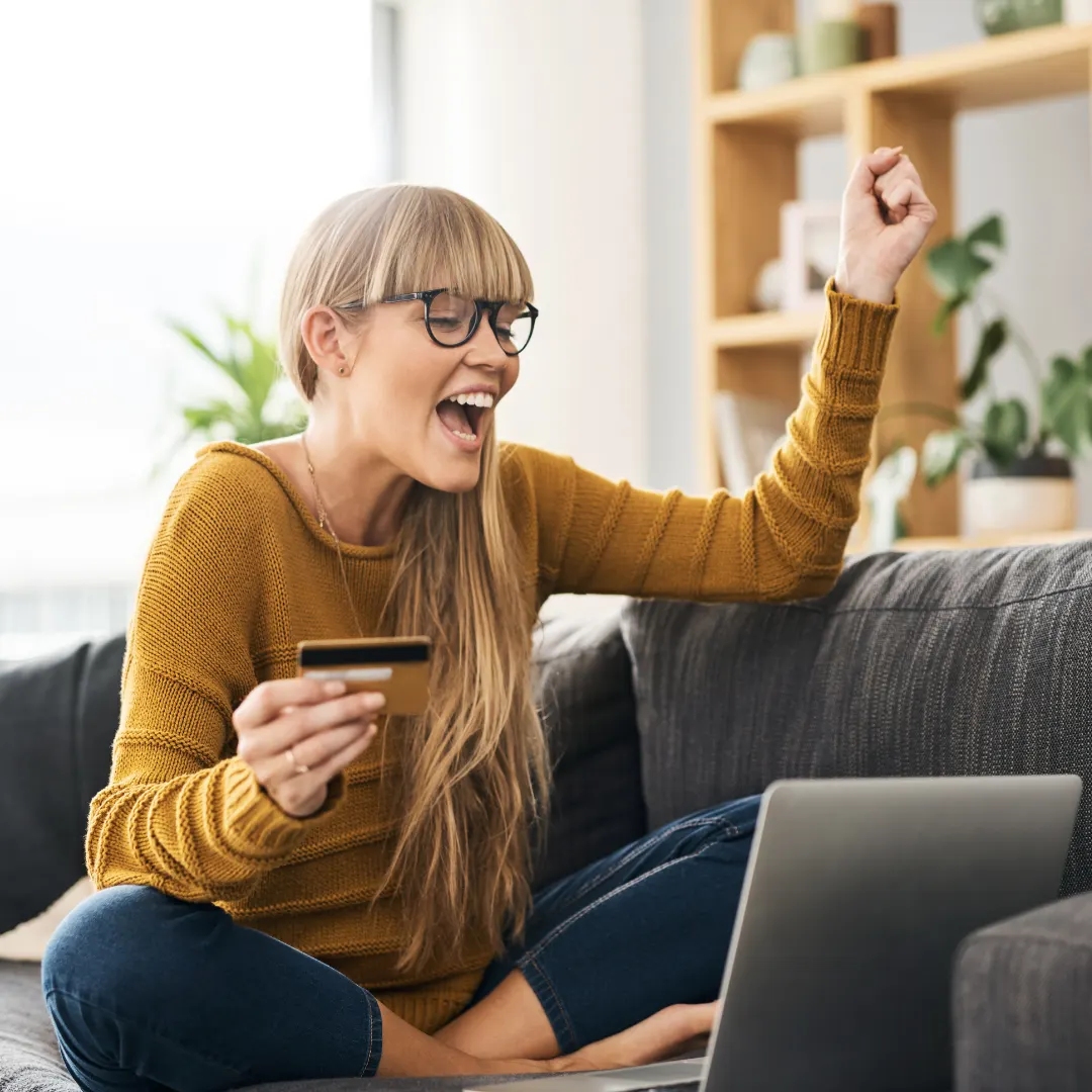 smiling woman holding a credit card while booking a stay on her laptop