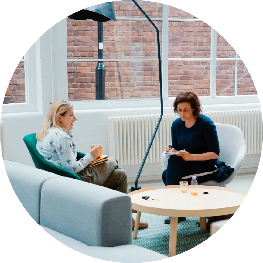 Two colleagues talking in a bright office lounge