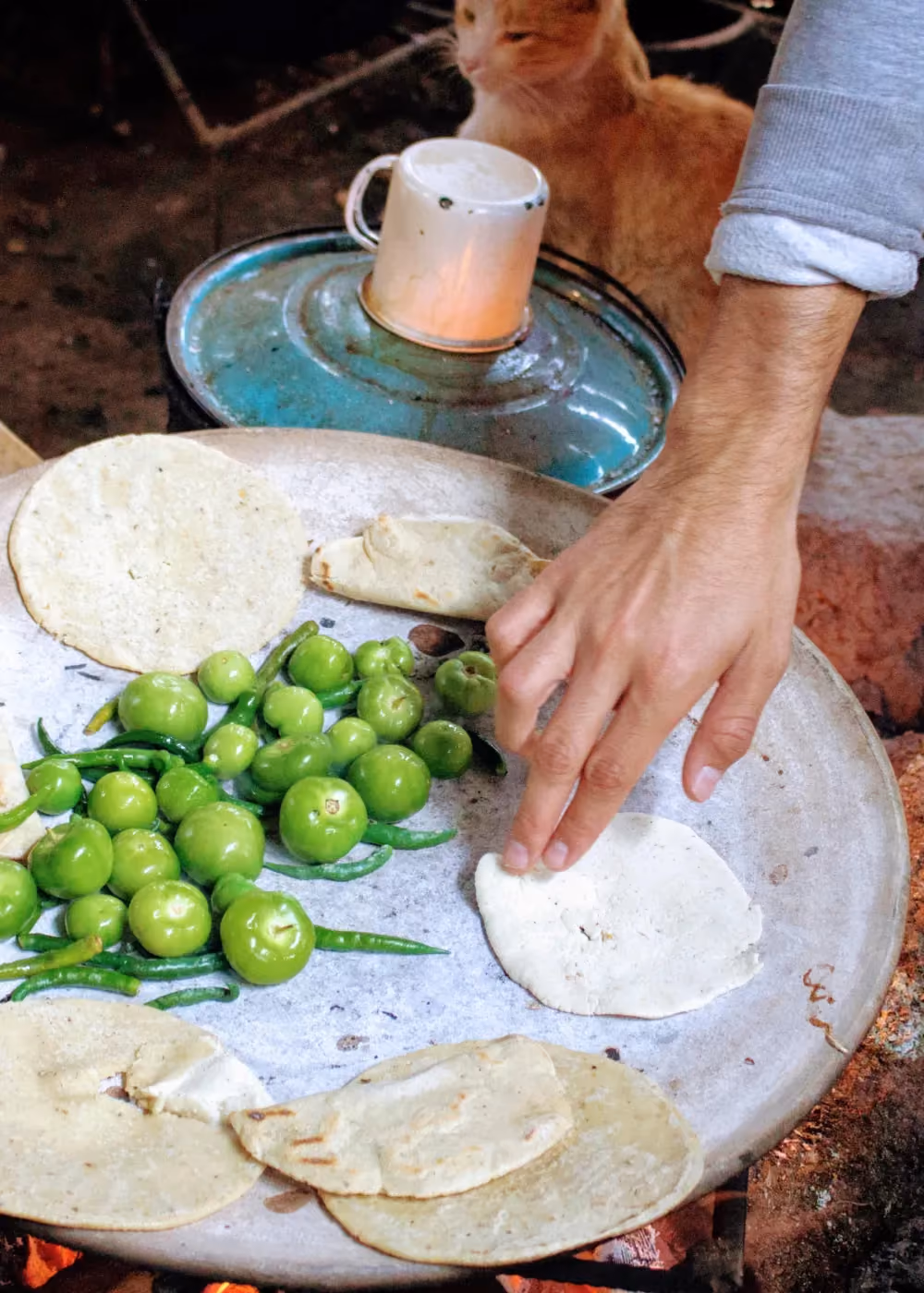 A hand touching a tortilla on a plate along with sA hand touching a tortilla on a plate along with some other vegetablesome other vegetables