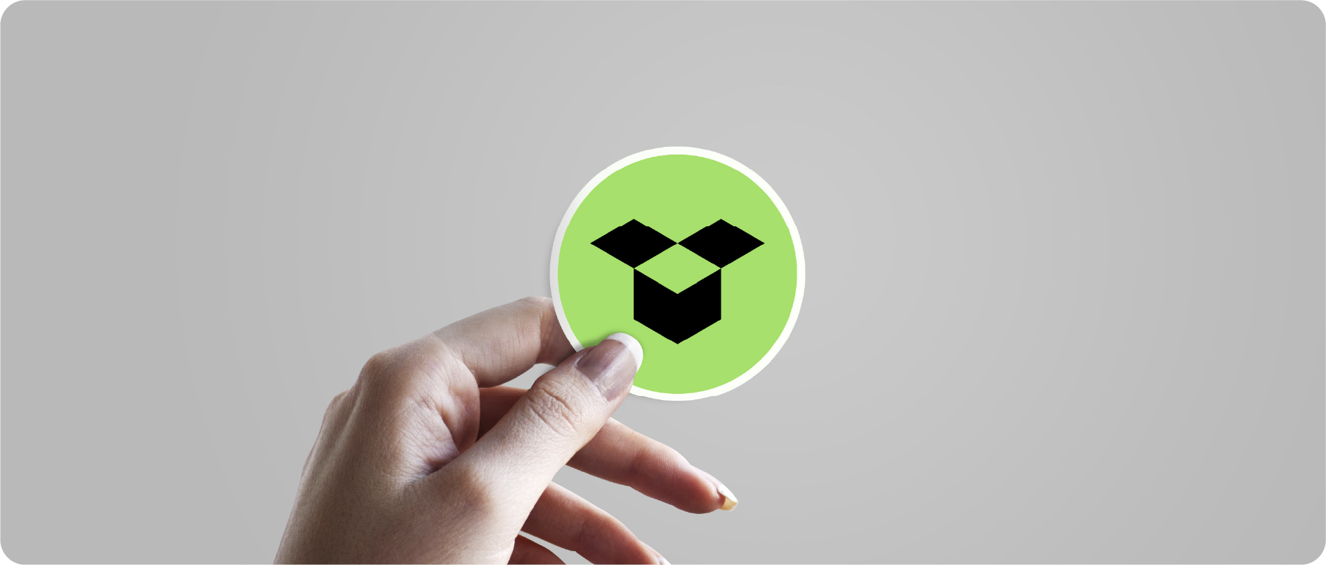 A hand holding a circular sticker mockup featuring a lime green and black geometric brand mark.