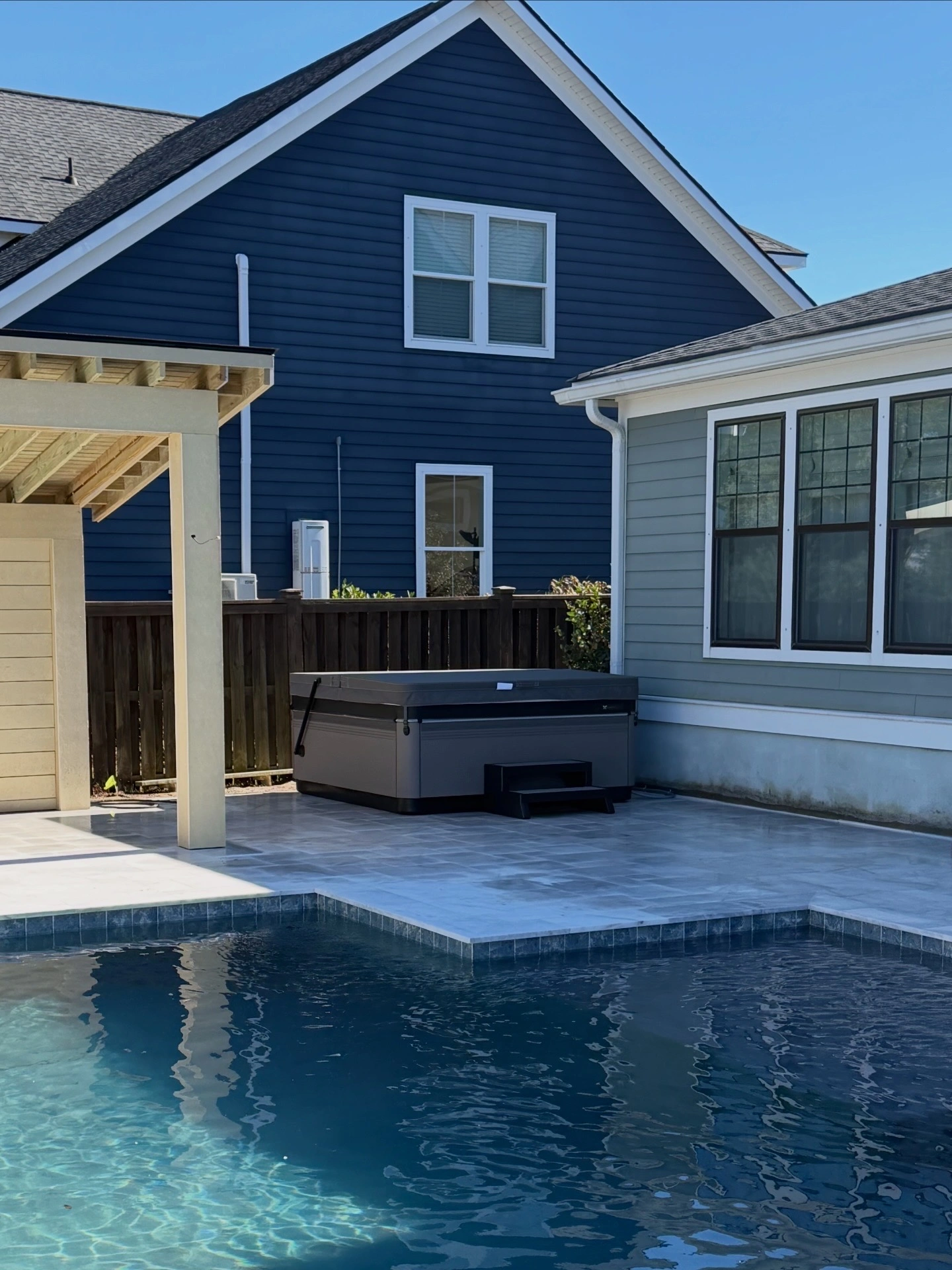 Caldera hot tub installed on a marble pool deck beside a custom gunite pool in James Island, South Carolina