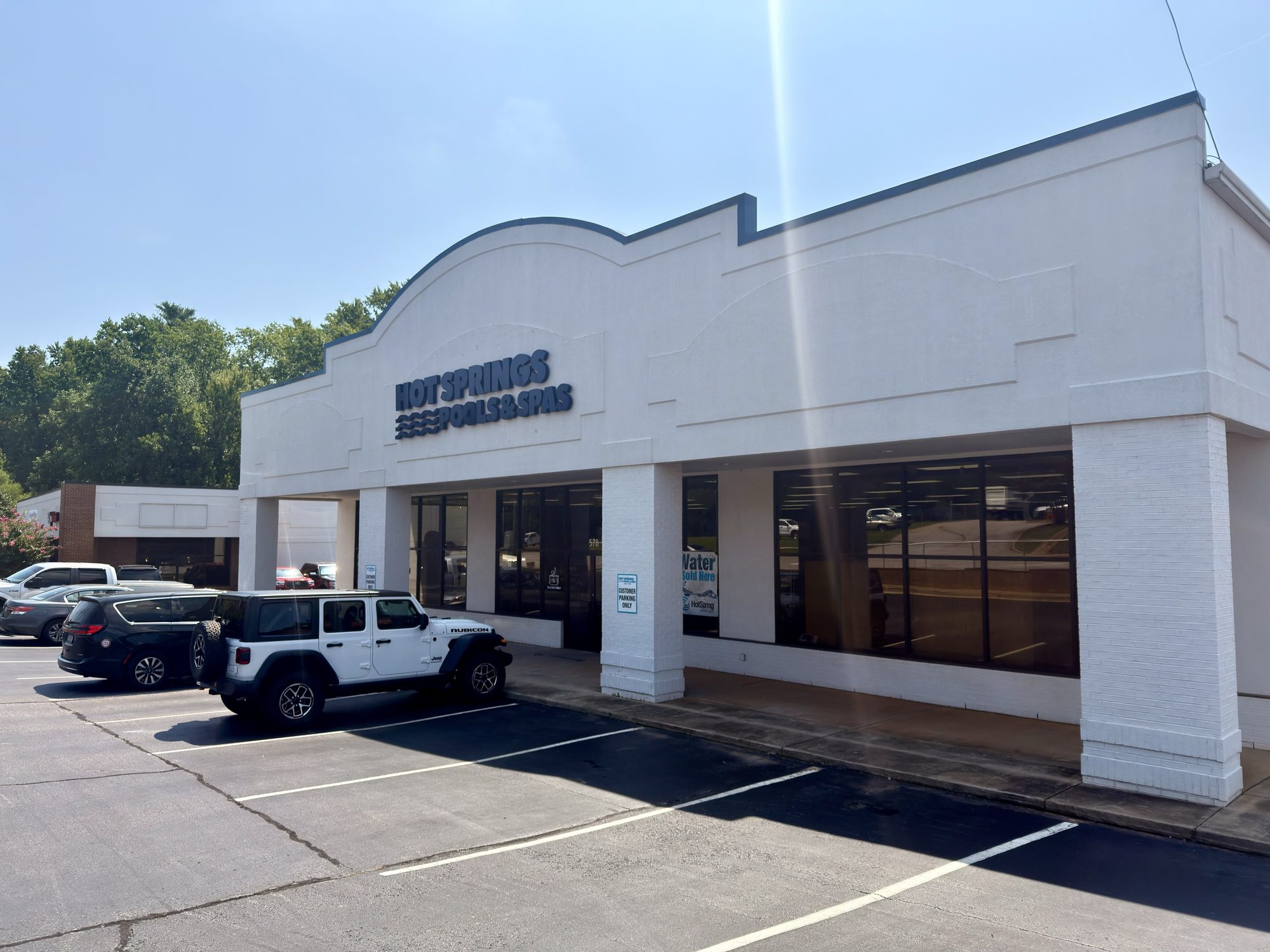 White storefront of Hot Springs Pools & Spas on Woodruff Rd in Greenville, SC, with blue signage above the glass windows