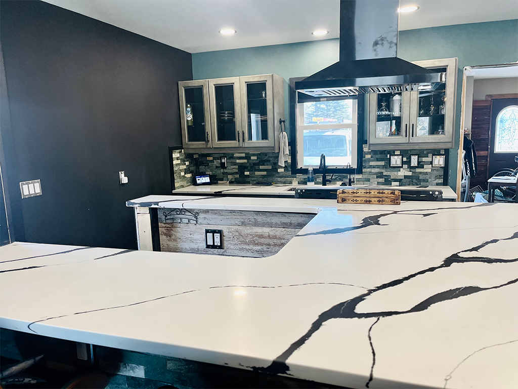 Dramatic Contemporary Design: Bold veined quartz kitchen countertop with teal cabinetry in Ankeny, IA - Quartz Impressions