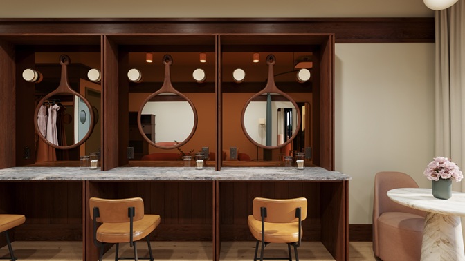 Interior of a stylish dressing area with three wooden-framed mirrors, four tan chairs, and a marble countertop, next to a round table with a pink flower arrangement.