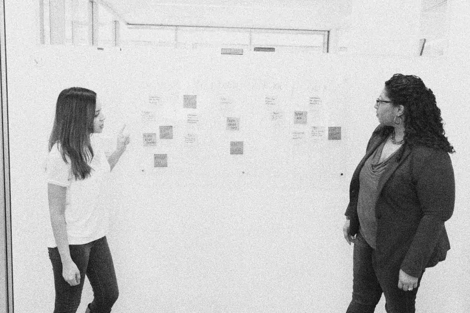 A design discussing their notes on a whiteboard to ensure the best results.