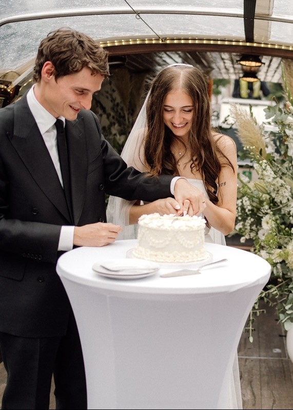 a bridal couple cutting a wedding cake on a salon boat