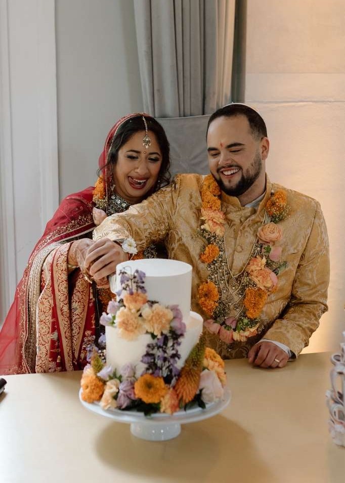Wedding couple dressed in colourful Indian wedding gowns cutting there wedding cake at Artis Amsterdam