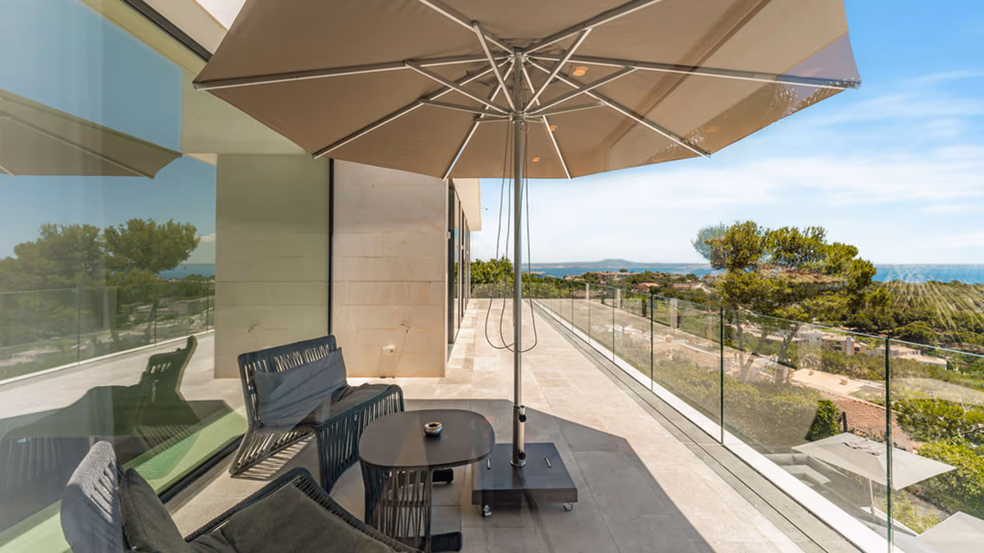 Terrasse mit Sesseln und Sonnenschirm.