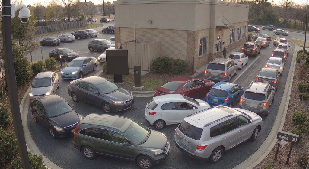 Aerial camera view of a drive-thru lane with cars overflowing into the parking lot