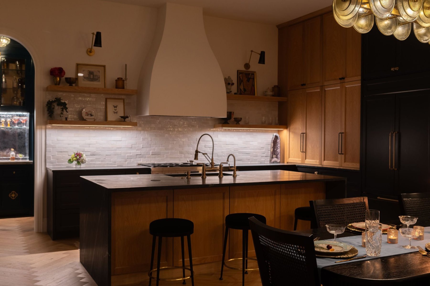 Kitchen at night with plaster hood, oak island, and lit shelves