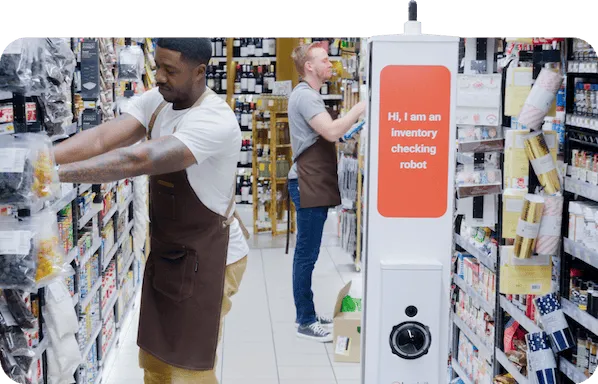 Two retail employees and a retail scanning robot in a store aisle