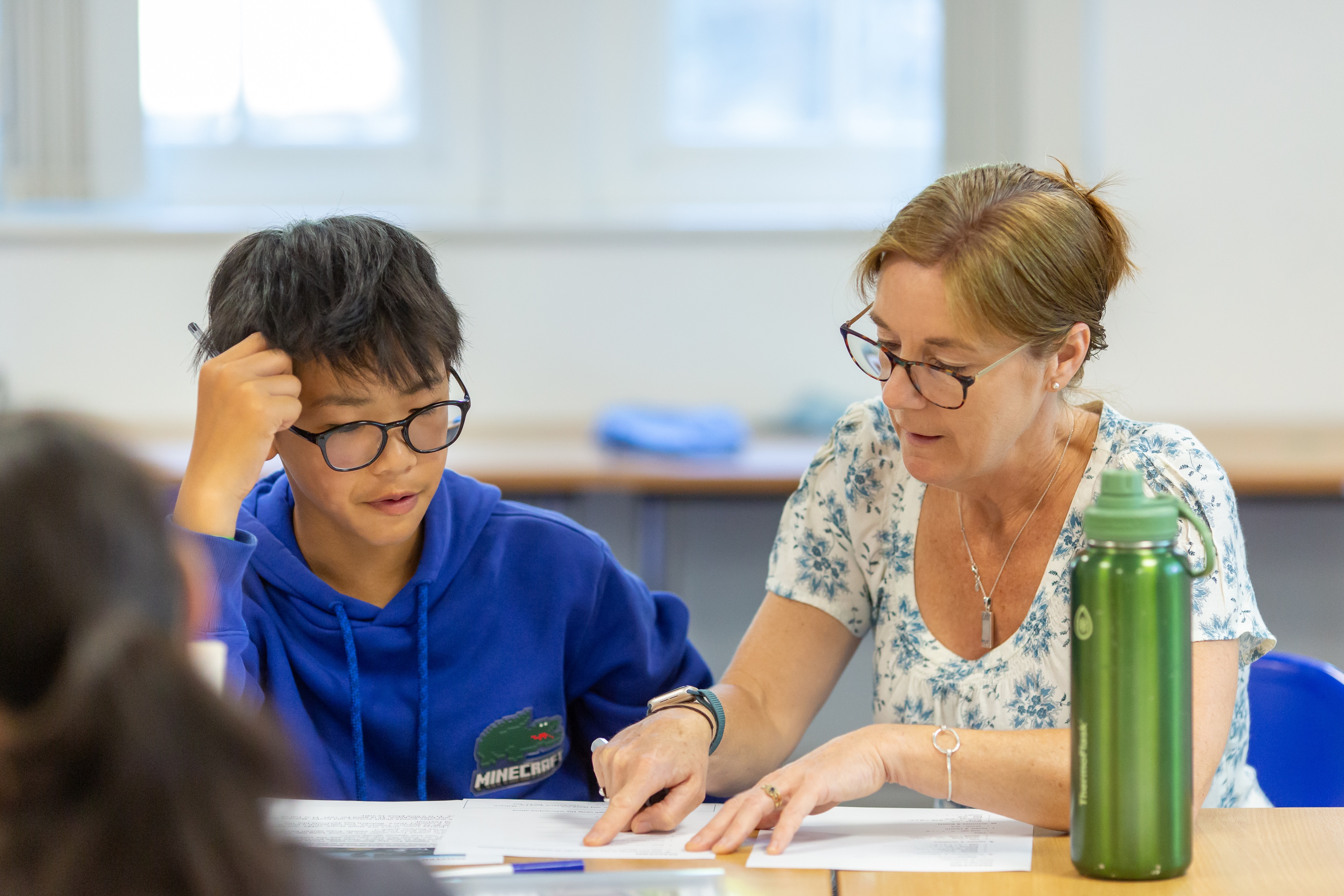 English lesson – a teacher helping a student during an English class at the Malvern College Summer School.