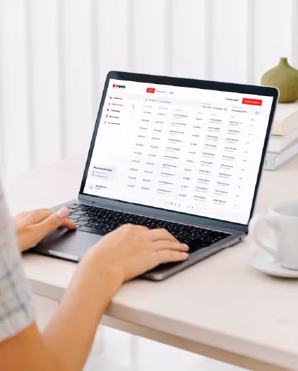 Osoba pisząca na laptopie, na którego ekranie wyświetla się panel z listą wpisów danych w formacie tabelarycznym.