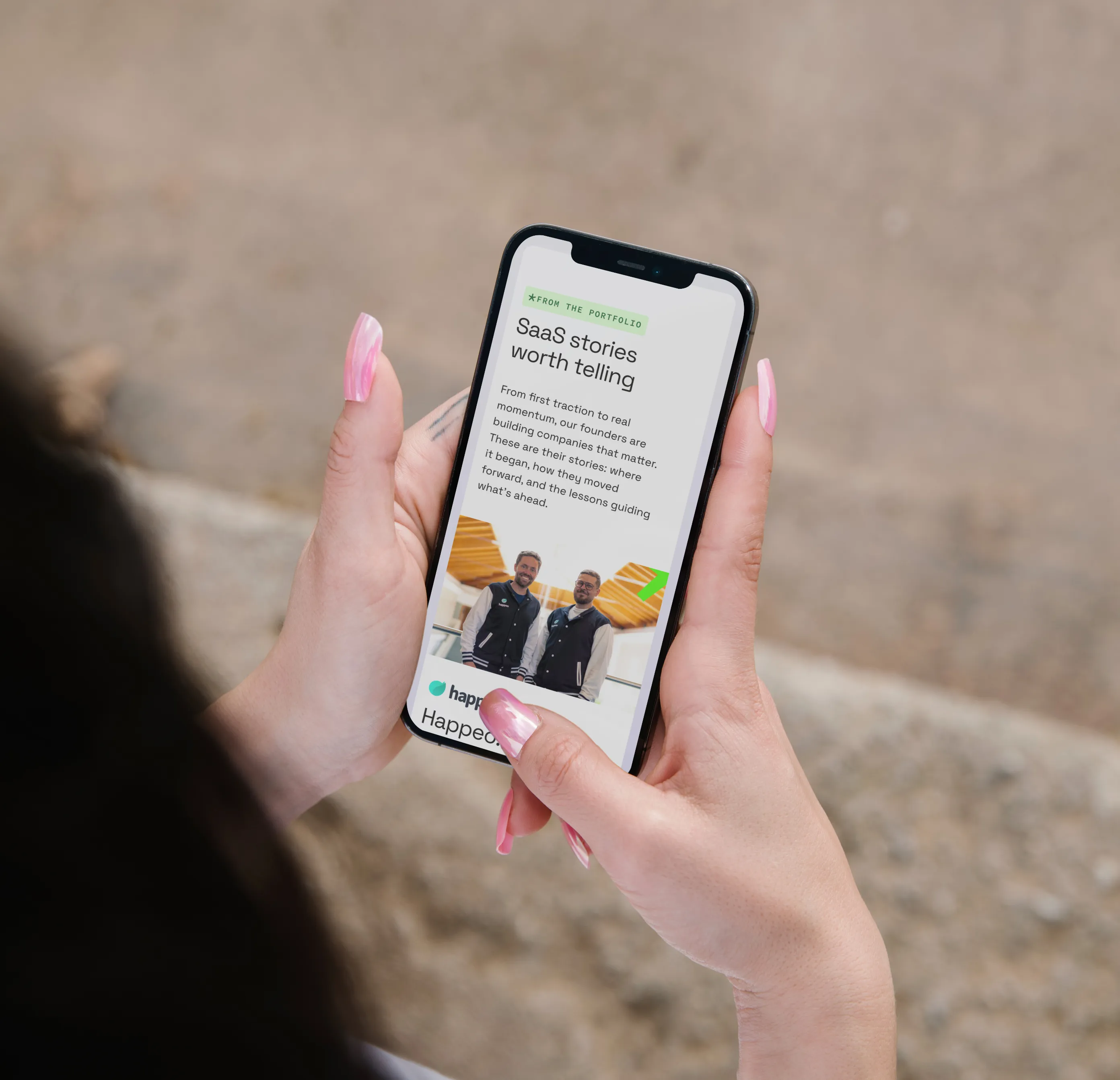 Hand holding smartphone with Vendep Capital mobile website open, showing a portfolio founder story article.