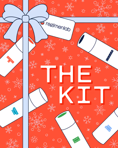 A flat lay of Regimen Lab's Kit featuring 5 of its most iconic products scattered around holographic gift wrapping paper, topped with a light blue bow and tag printed with Regimen Lab's logo