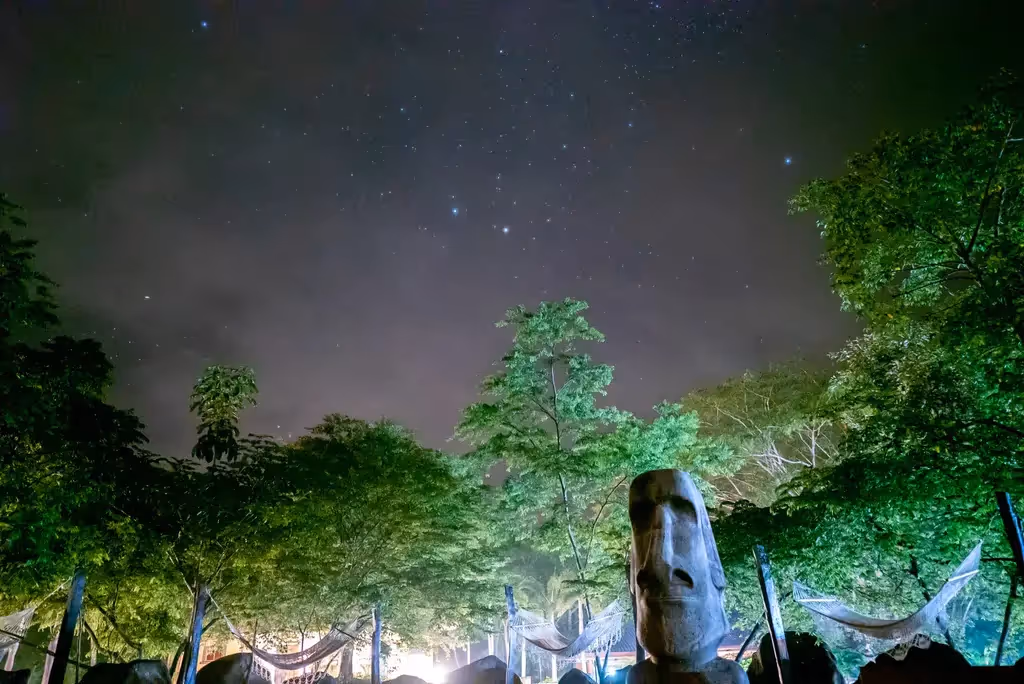 People participating in a wellness or healing ceremony at Rythmia, set in a tropical outdoor environment.