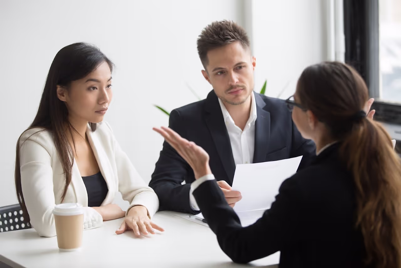One man and two women in professional dress conversing to each other