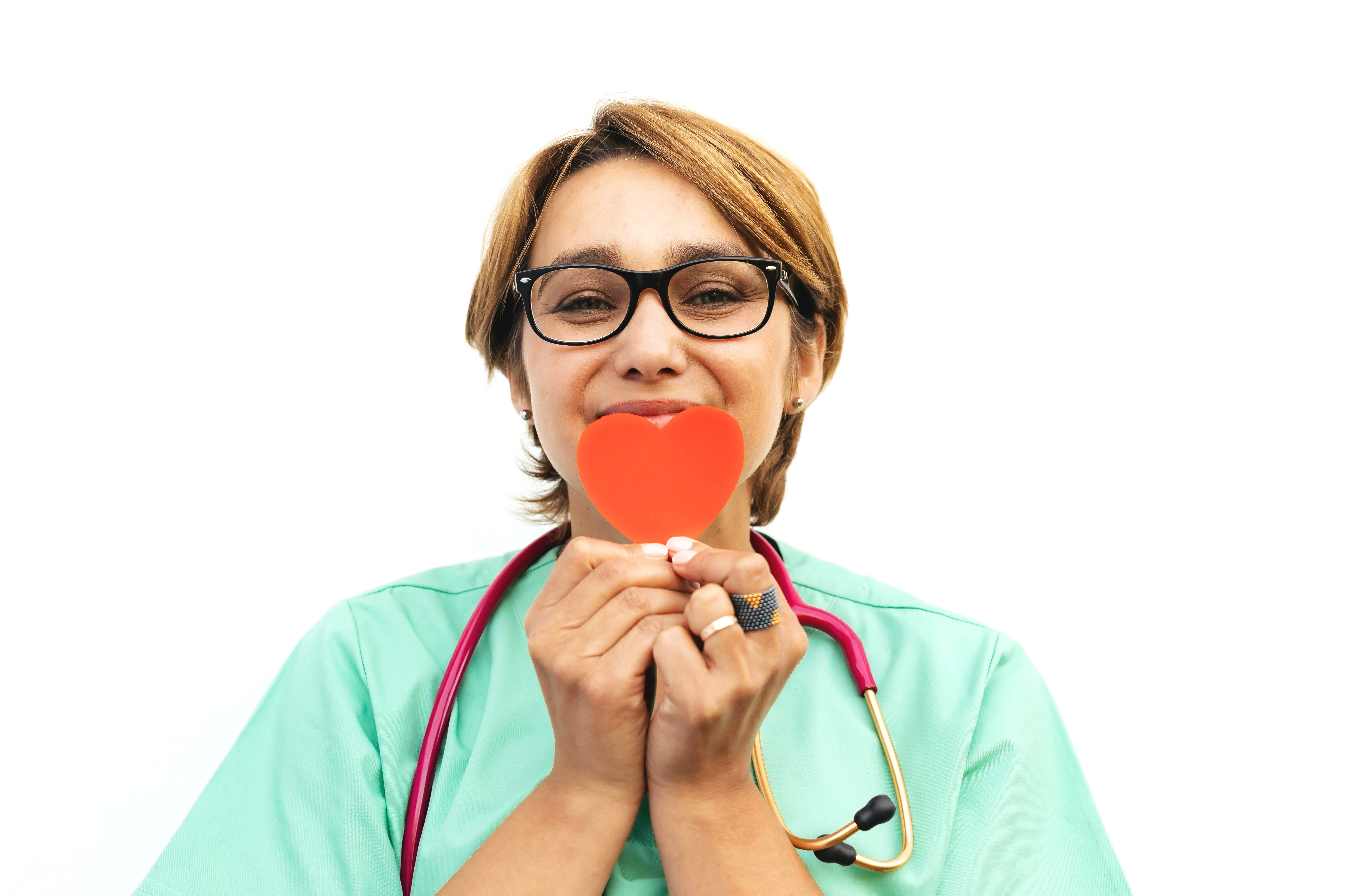 Medical assistant holding a red paper heart in front of her face