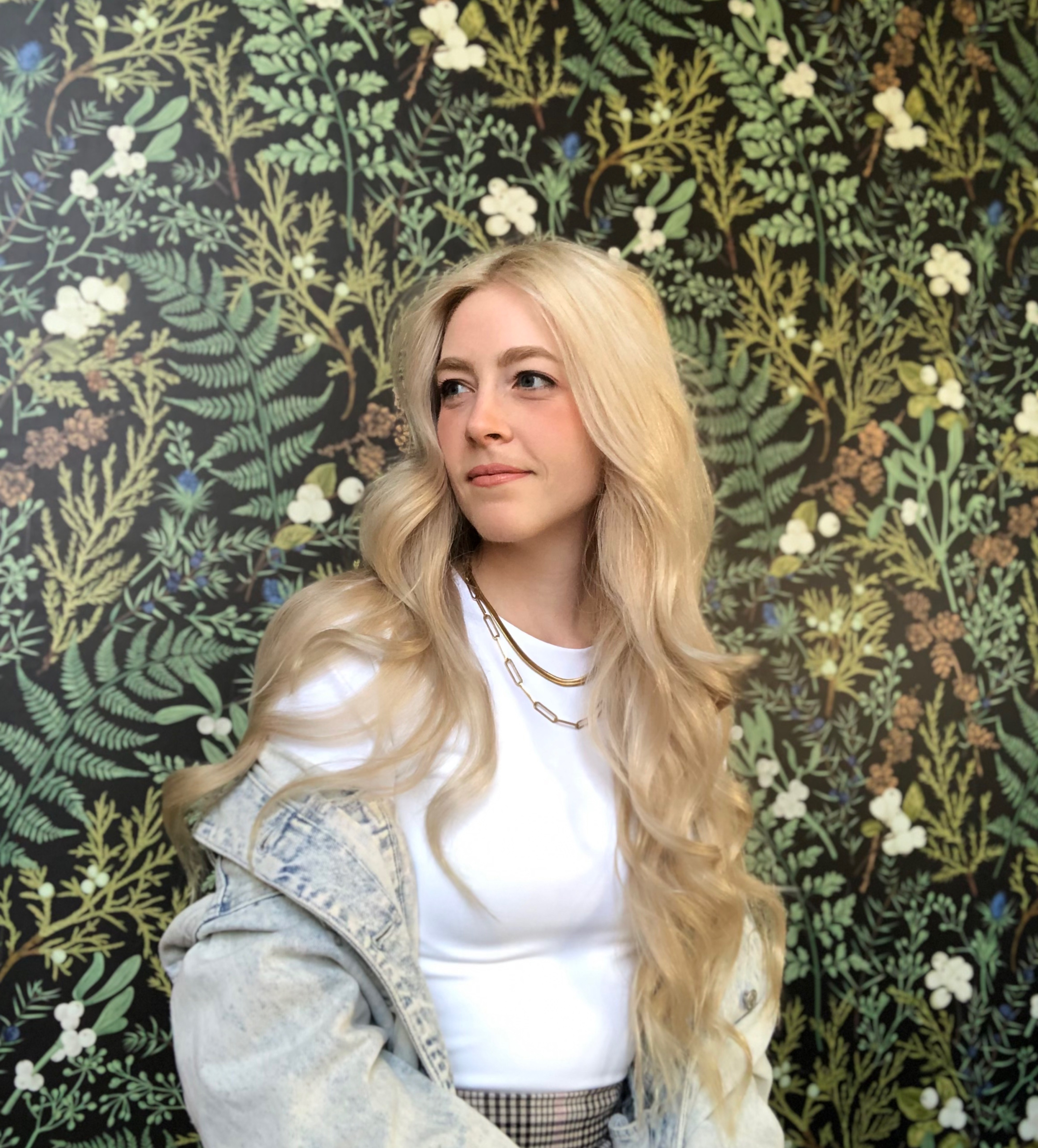 Portrait of Heather Ostertag in a white shirt in front of a green leaf wallpaper background. 