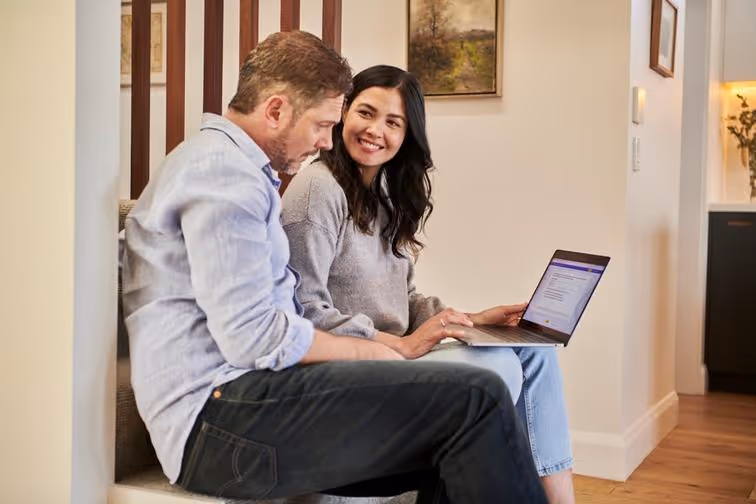 A professional workspace with people collaborating, using laptops, and reviewing documents.