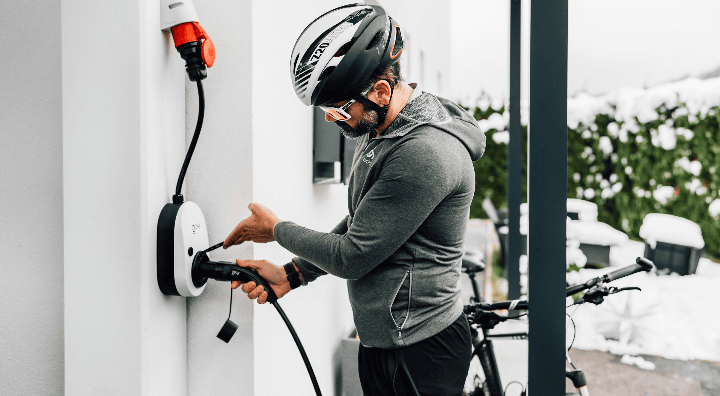 Man in cycling gear plugging in an electric bike charger