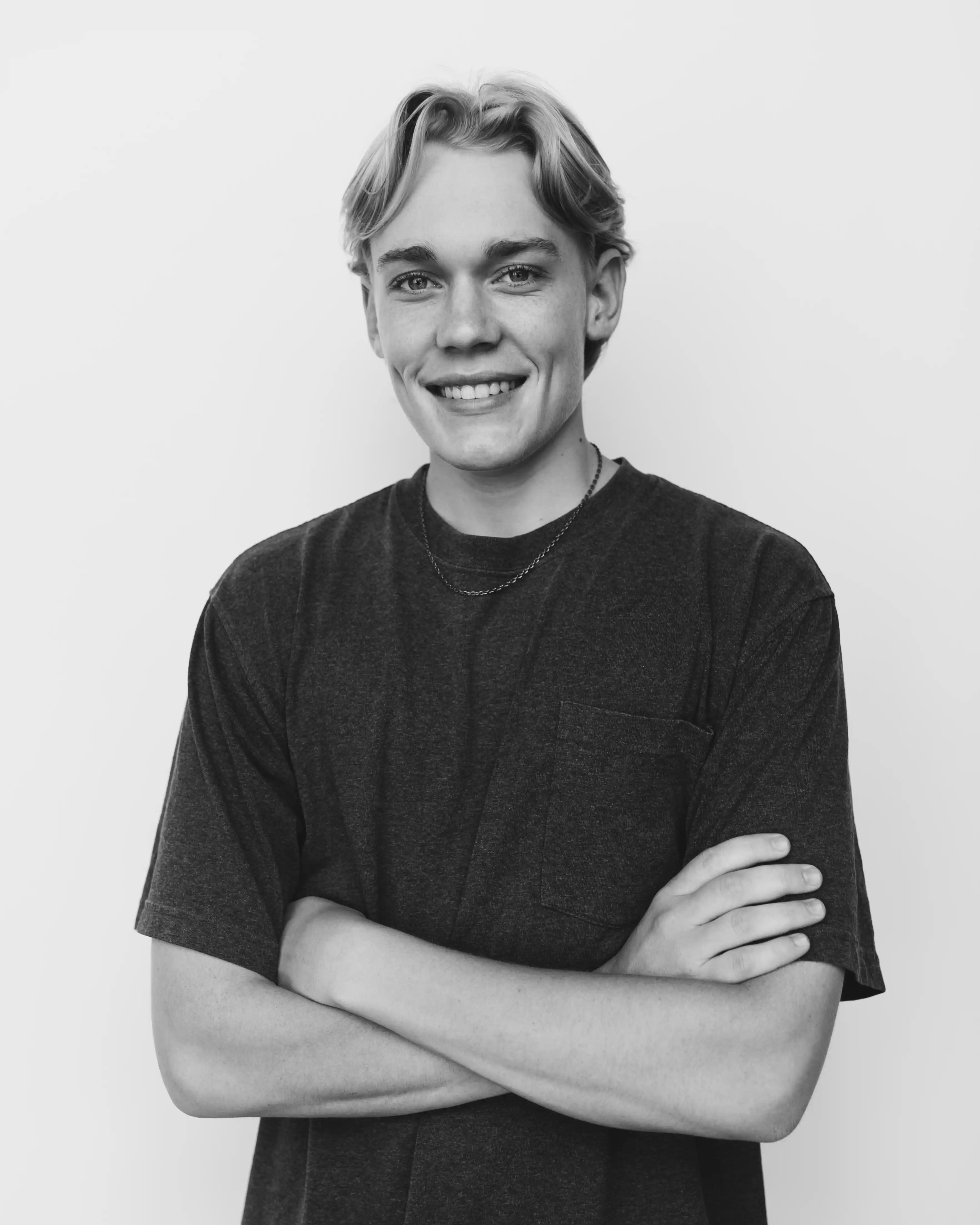 Smiling man with wavy blond hair, standing against a plain background.