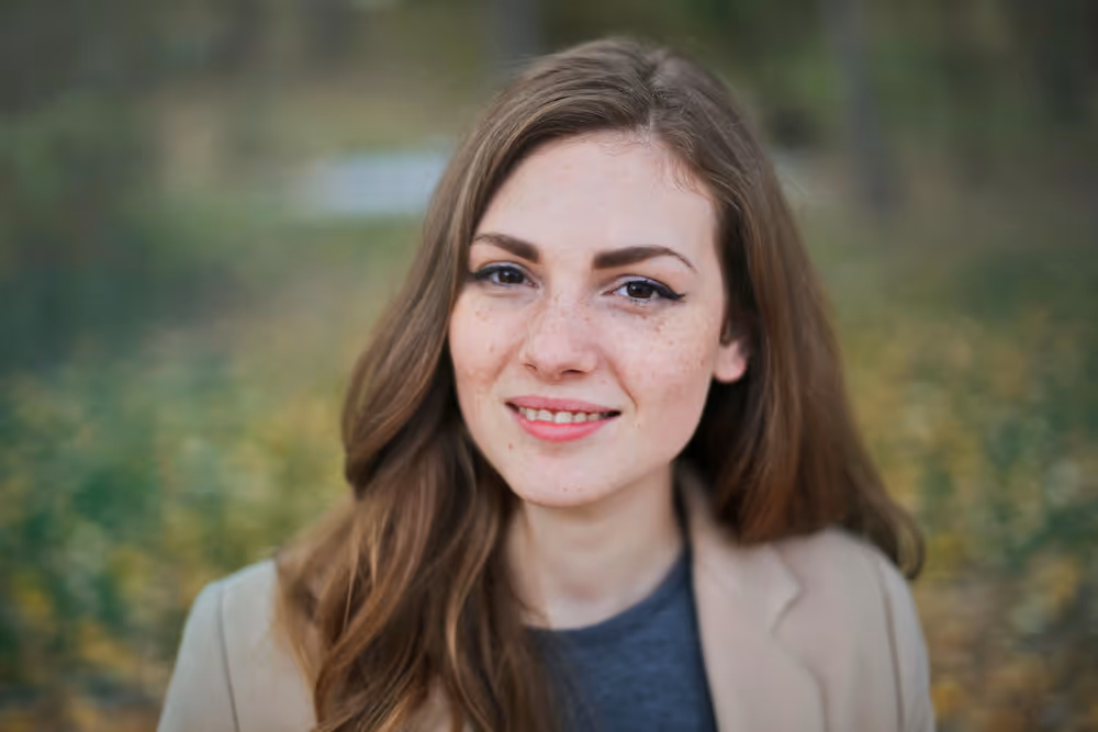 smiling woman with park and fallen leaves behind her