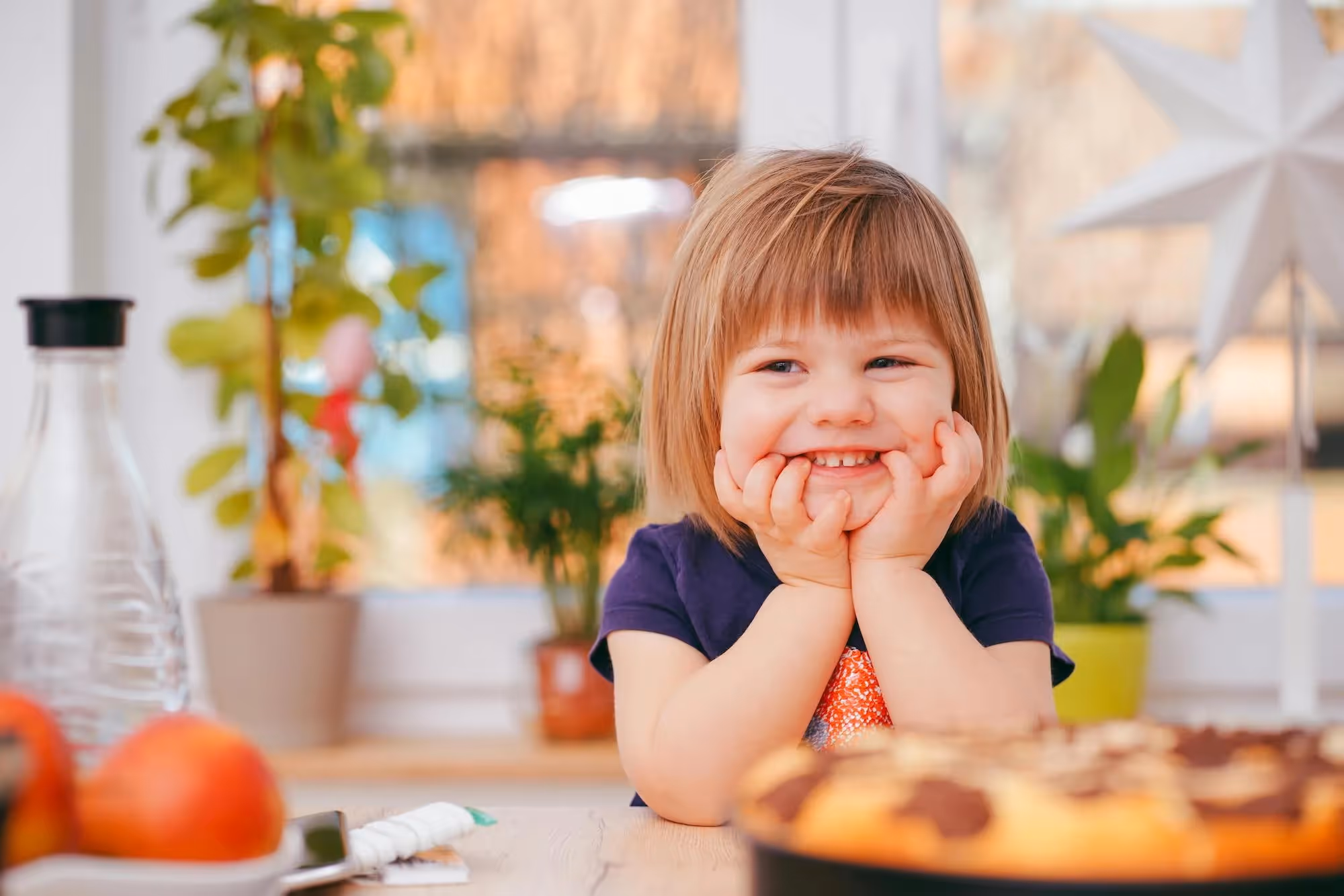 a child smiling at a table with a pie in the foreground