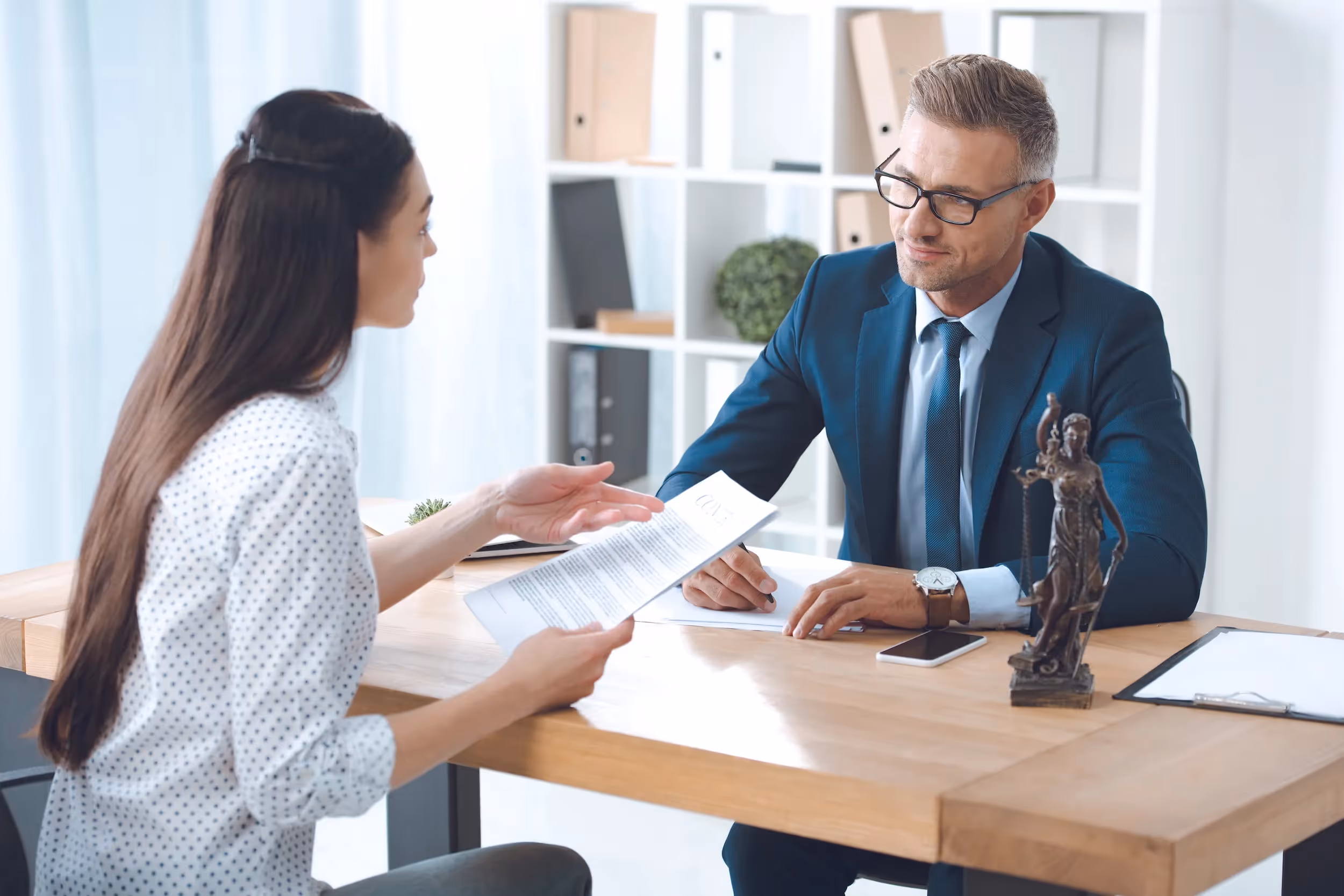 woman meeting with her family lawyer in his office and discussing a legal document