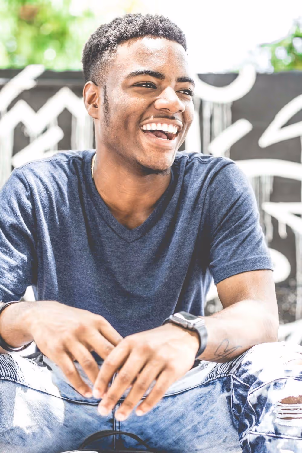 a young man smiling while glancing away from the camera