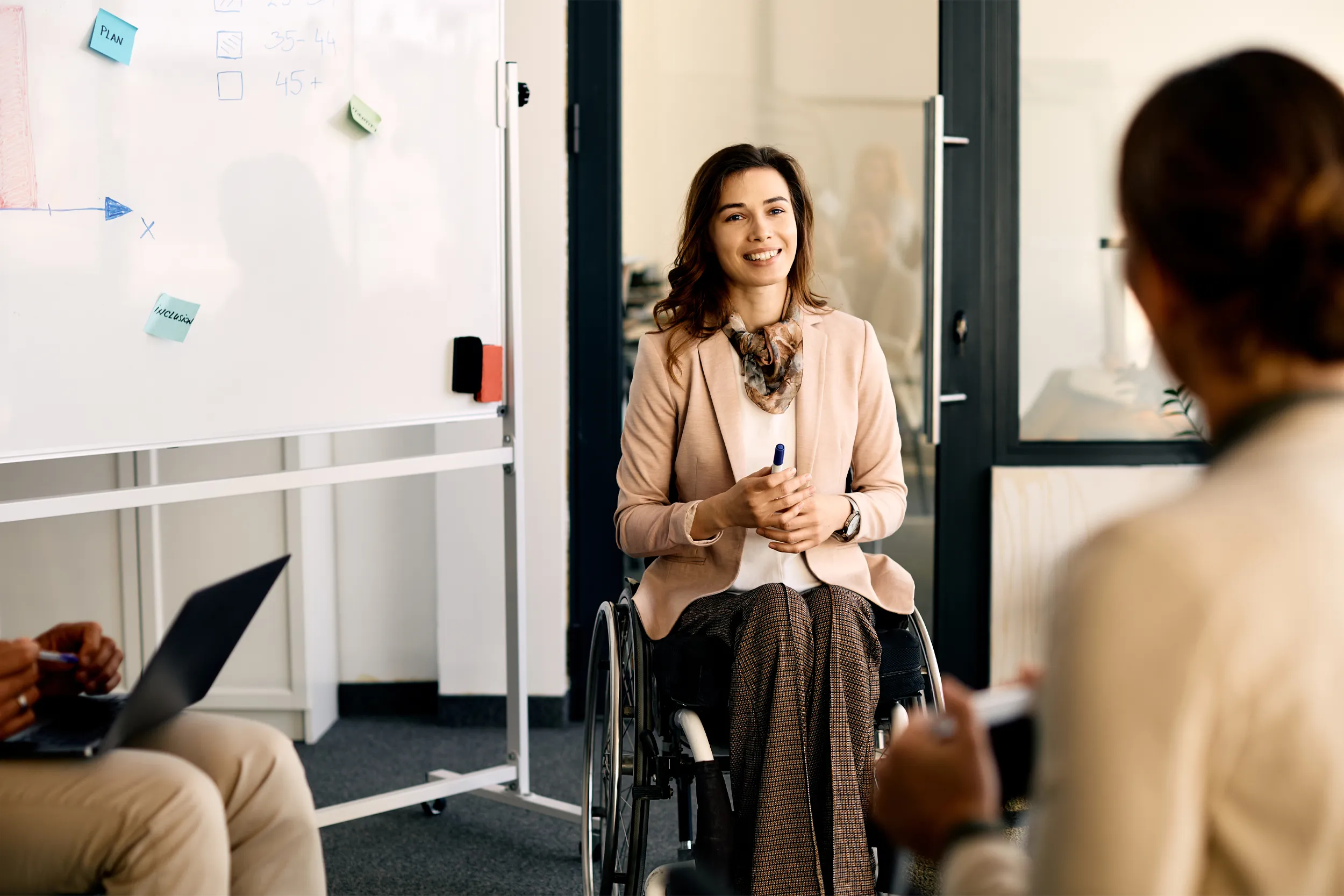 Woman sitting in a wheelchair in front of a white board 