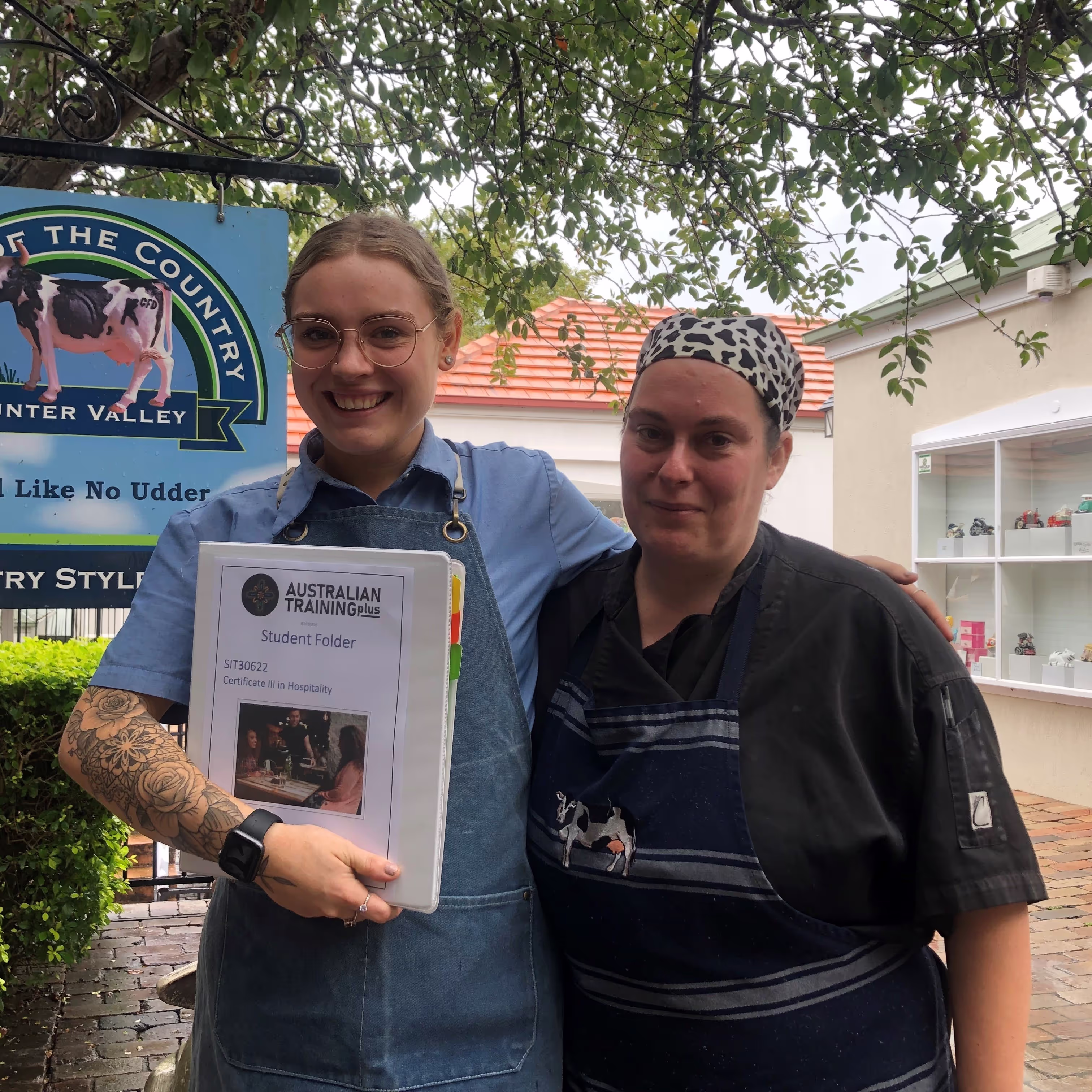 2 women standing outside holding a study folder
