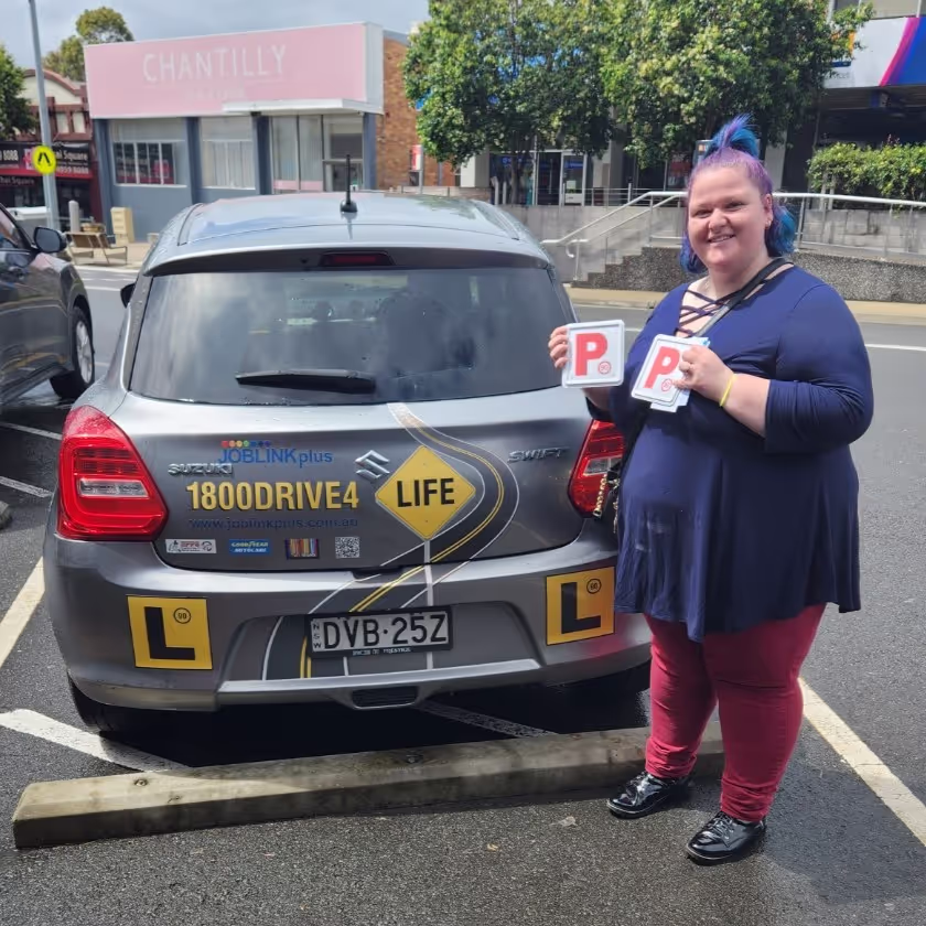 Woman in front of learner vehicle holding up P plates
