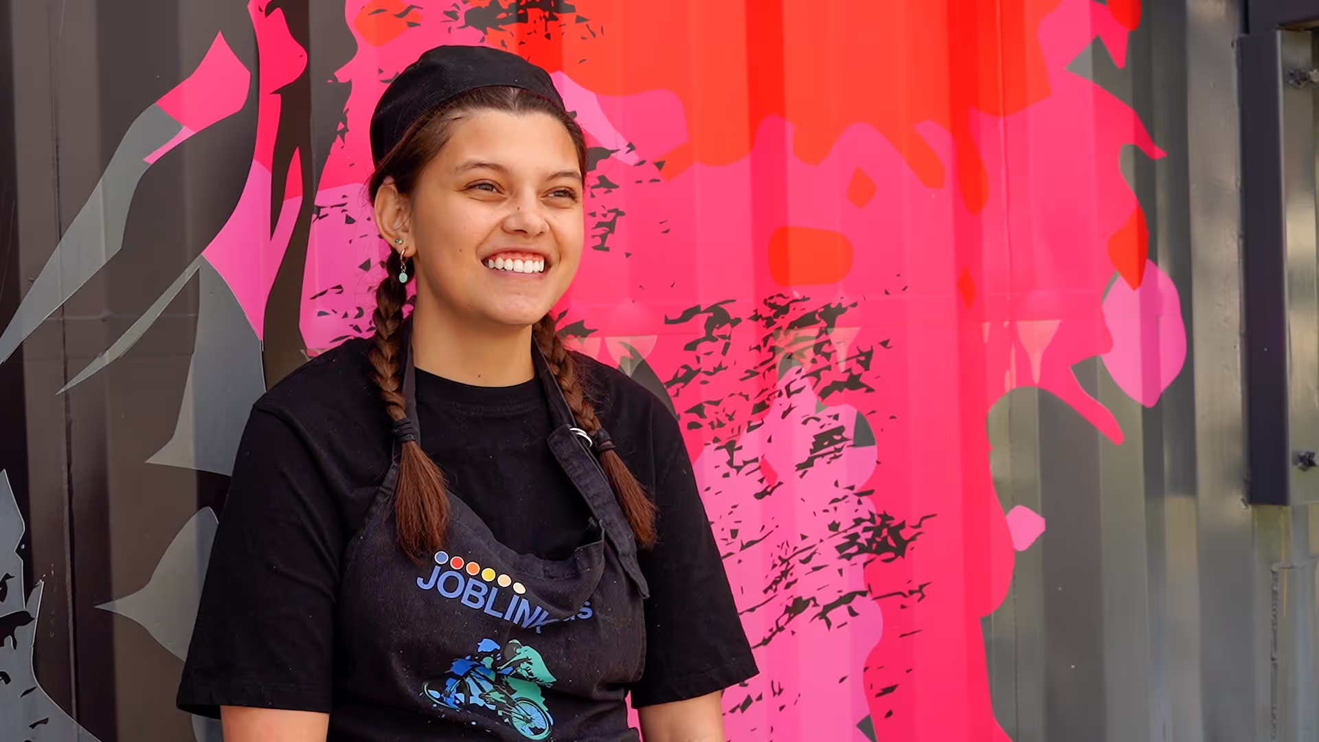 A young girl sitting in front of a coloured background