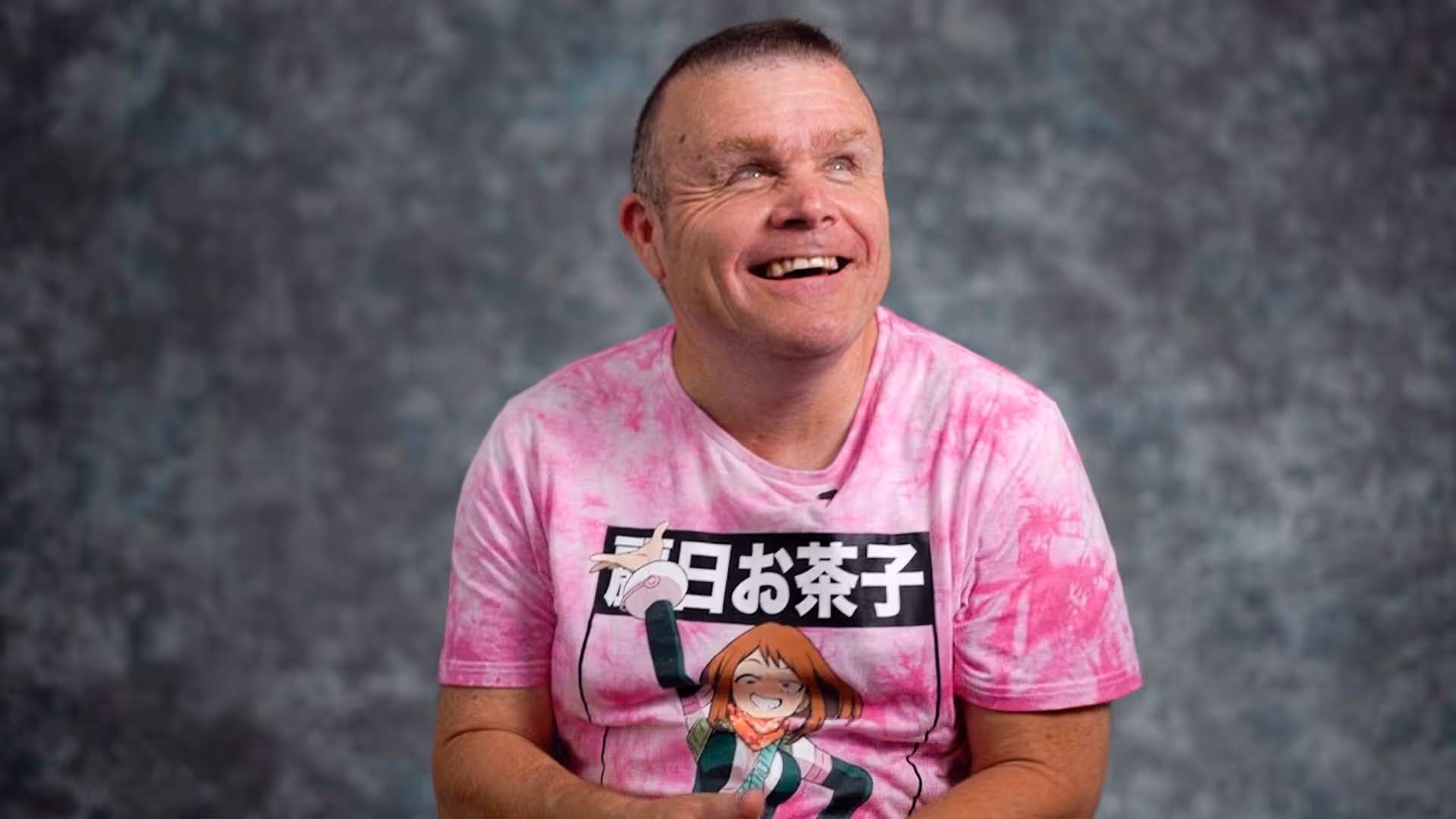 A man wearing a pink shirt sitting down.