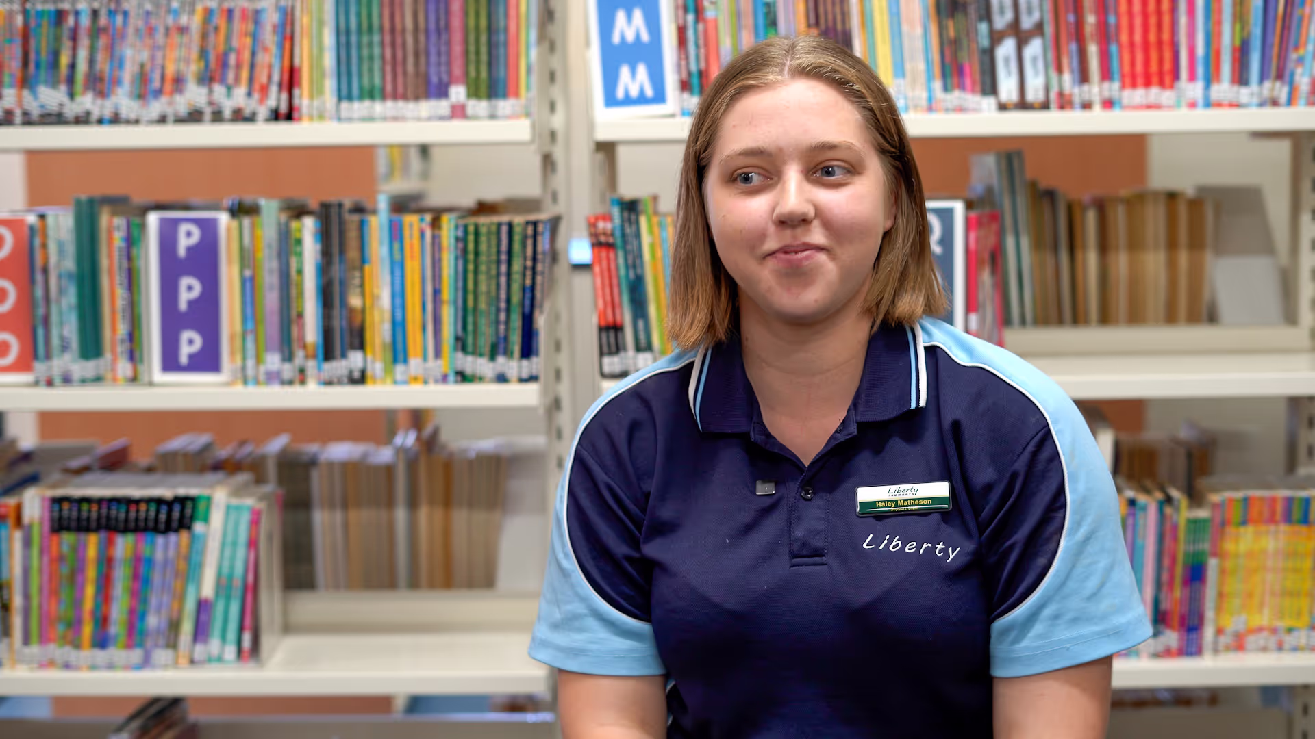 A girl sitting in front of a bookshelf