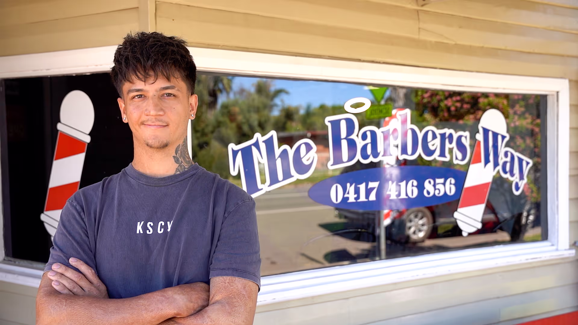 A young man standing in front of a barber shop window