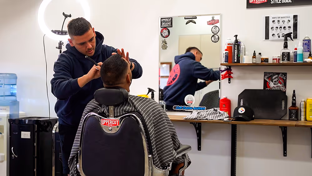 A man cutting another man's hair at a salon