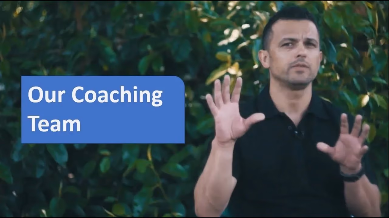 Man in black shirt gesturing with his hands next to text reading Our Coaching Team on leafy background.