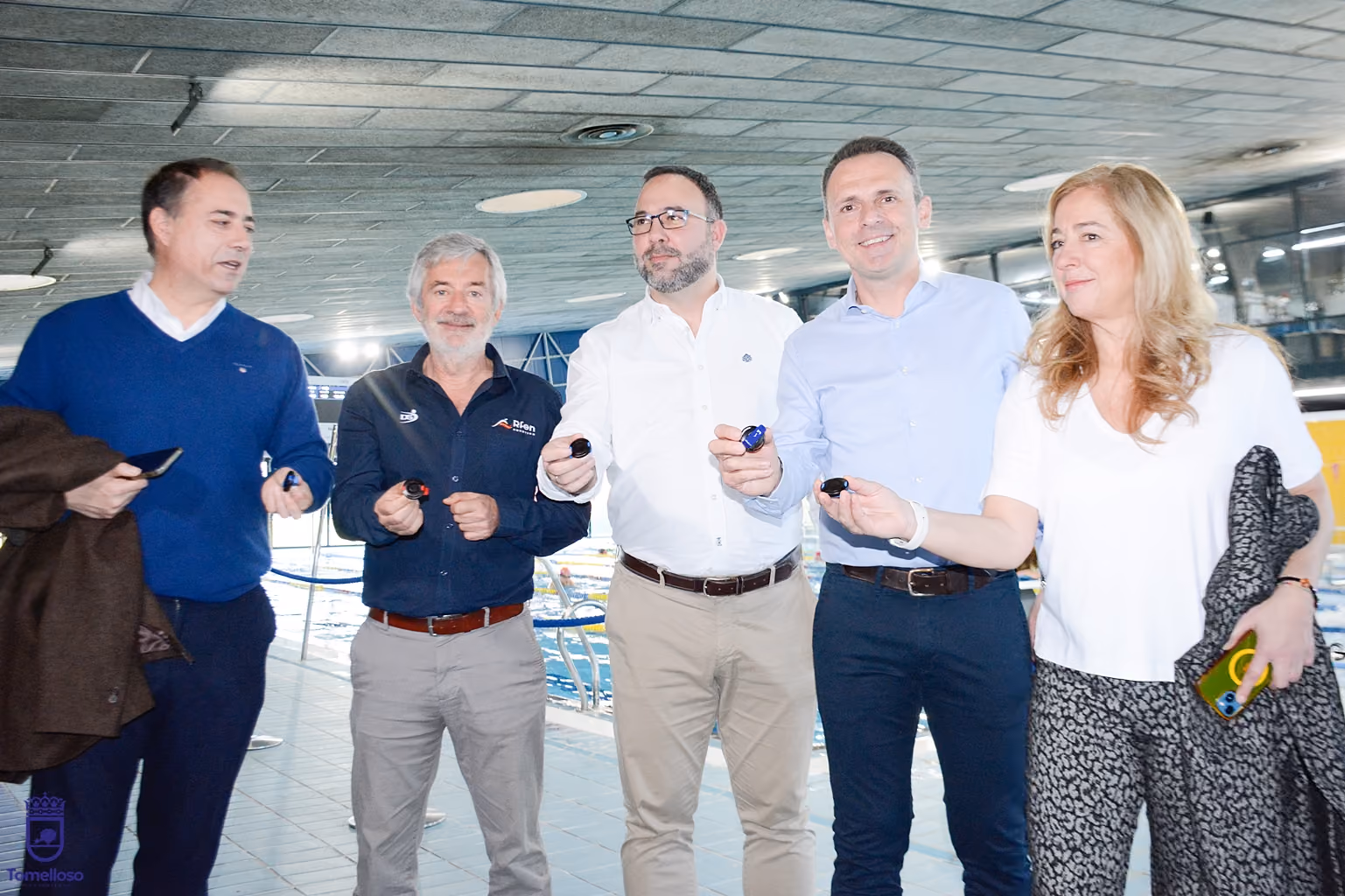 Participantes en la presentación, muestran el dispositivo que llevarán los nadadores.