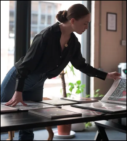 a woman leaning over a table looking at a magazine