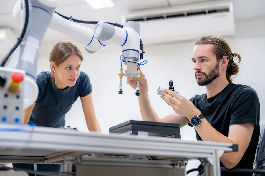 Two engineers working on a robotic arm