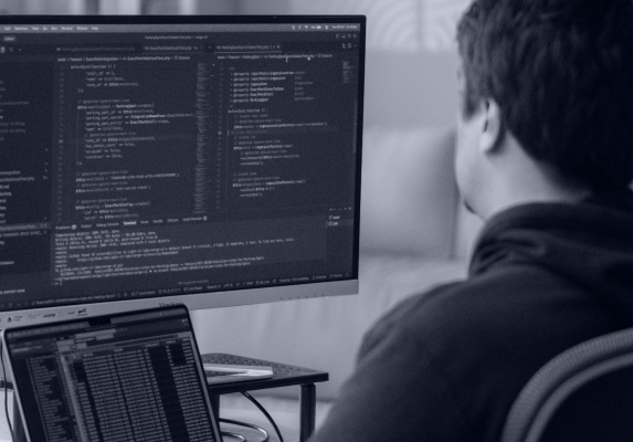 A developer reviewing code on a large monitor, illustrating the technical depth required in EHR data migration