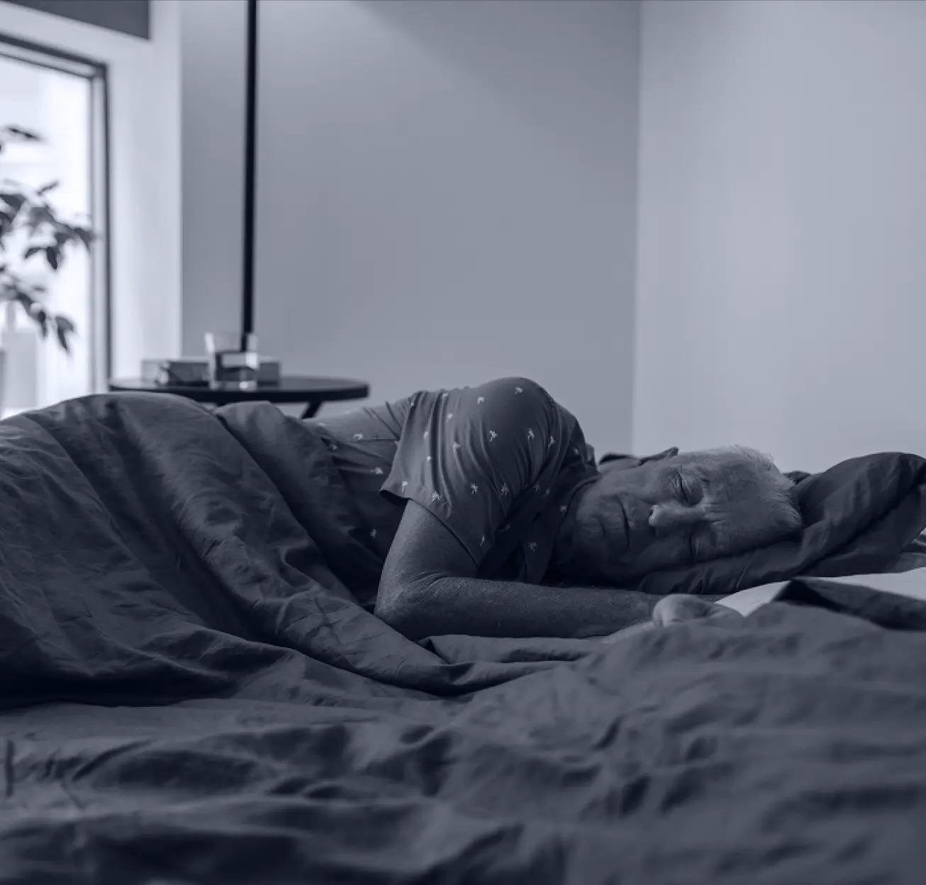 Elderly person resting peacefully in bed, illustrating the importance of quality sleep for senior living residents