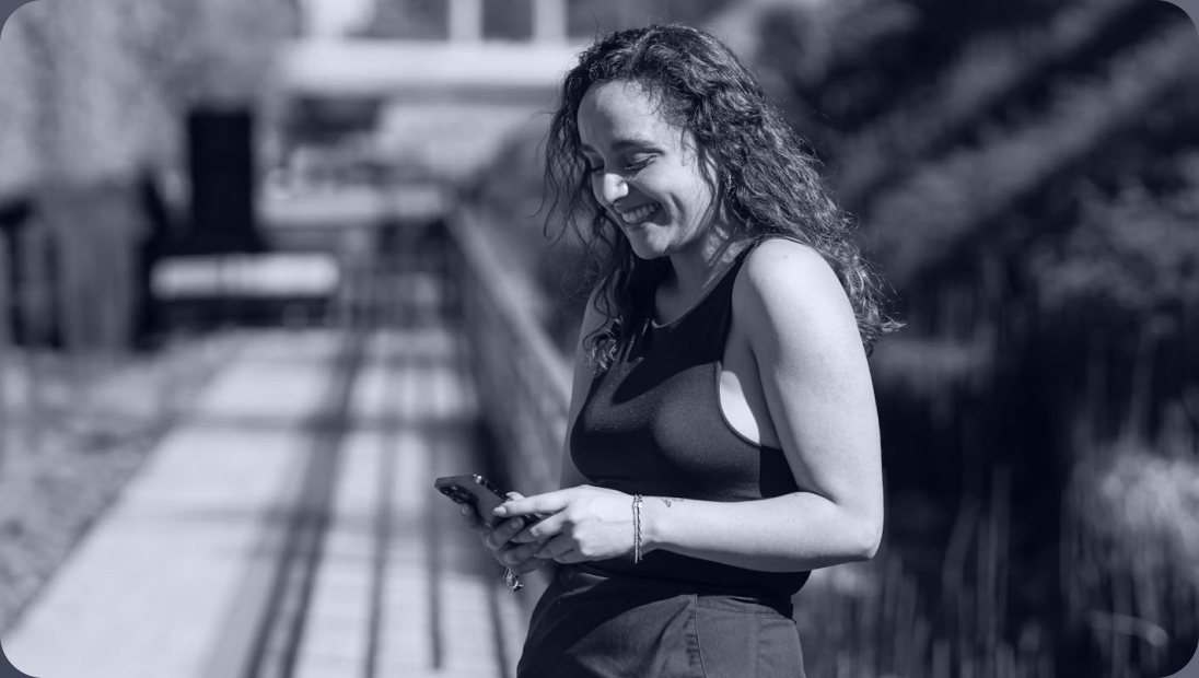 Woman smiling while checking her phone outdoors
