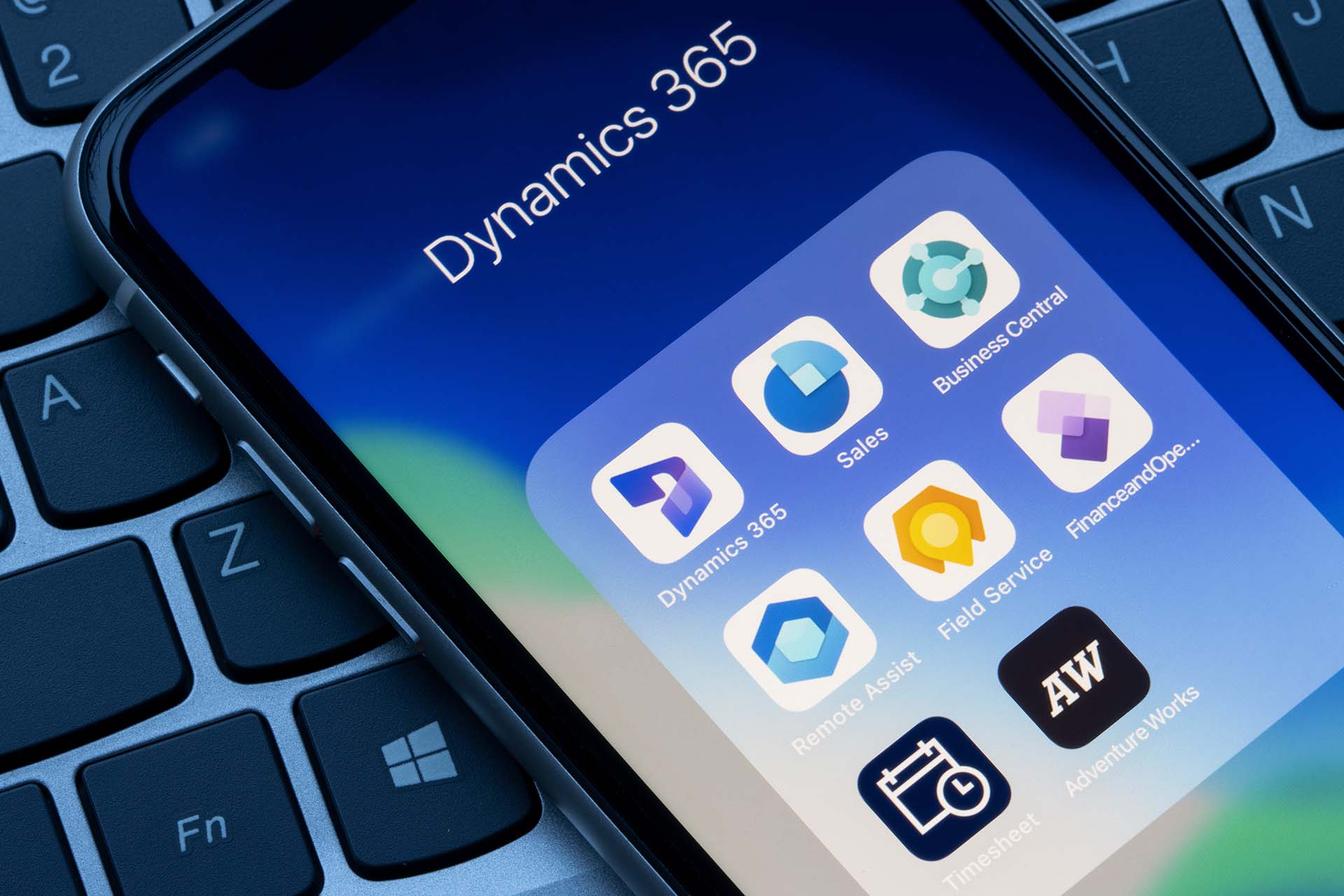 iPhone on a laptop, open folder with Microsoft Dynamics 365 apps.