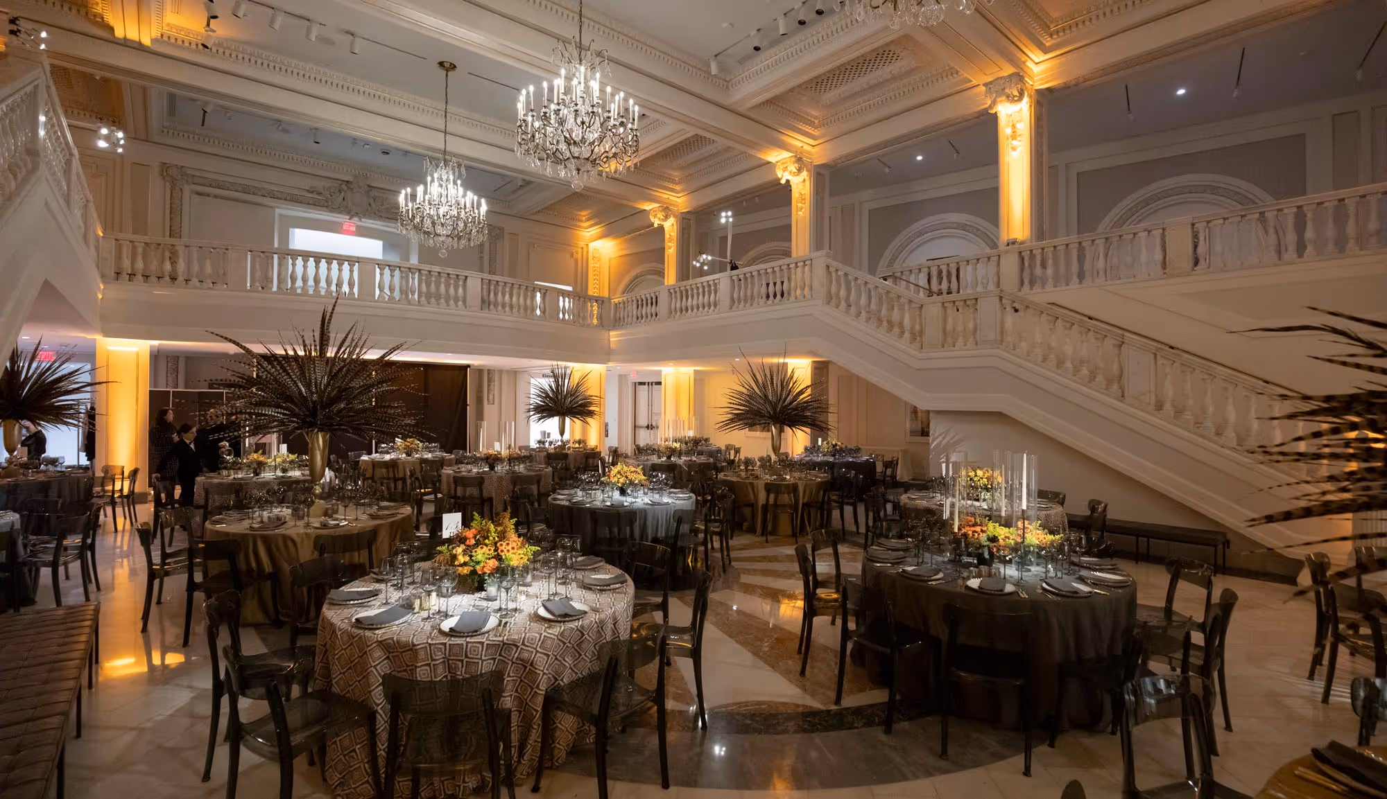 Elegant banquet hall with multiple round tables set for a formal event, decorated with floral centerpieces and chandeliers.