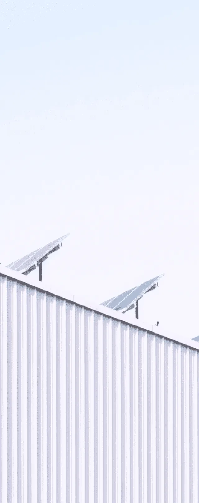 Solar panels sit on top of a roof on a bright day.
