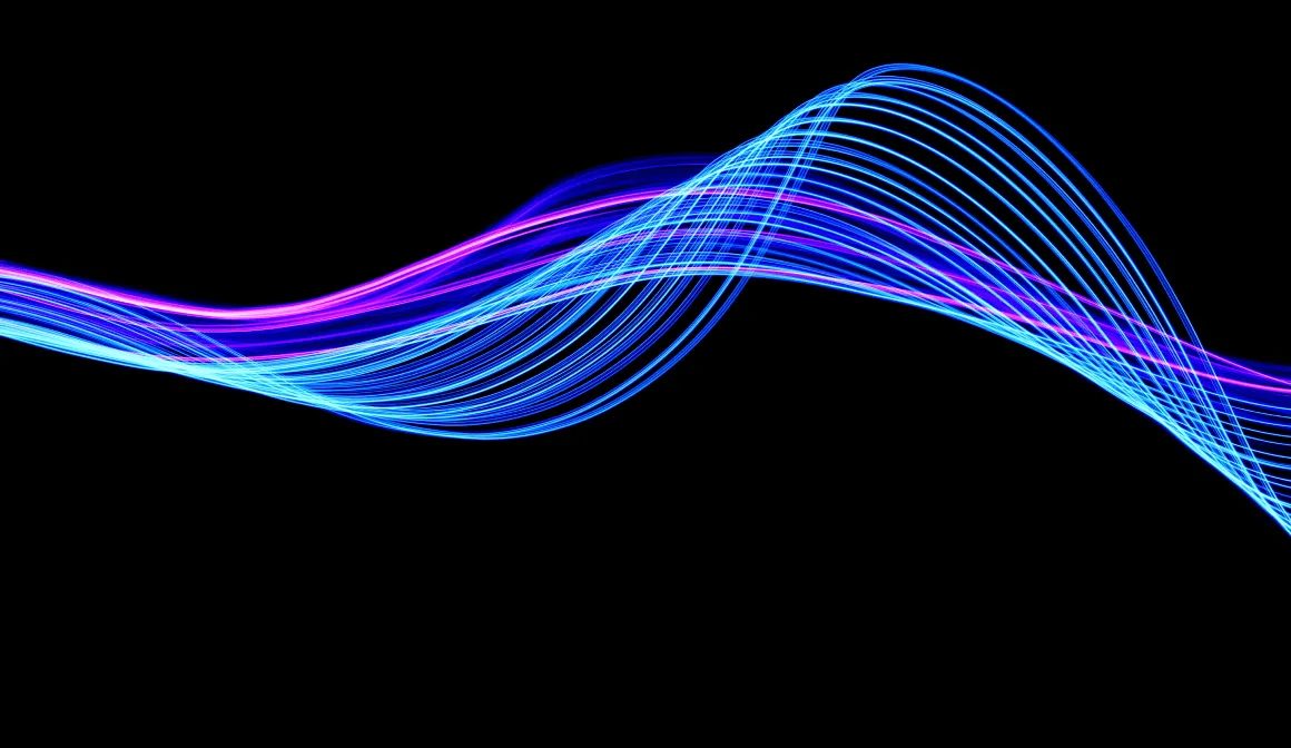 A large burst of colors ranging from blue to pink move in waves across a black background.