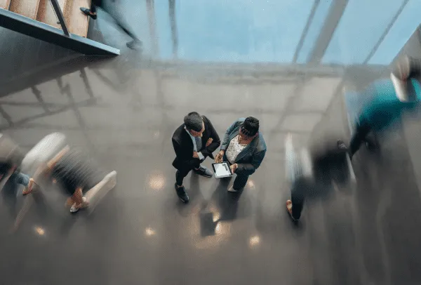 Two employees talk in an office setting, while the world continues to move by them quickly.